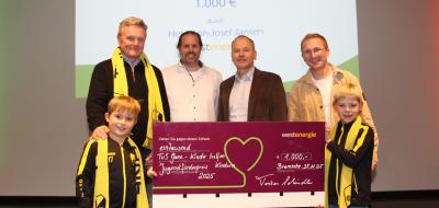 Sechs Personen mit einem symbolischen Scheck stehen auf einer Bühne.