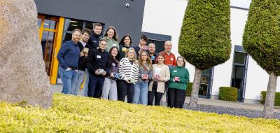 Eine Personengruppe steht vor einem Firmengebäude.