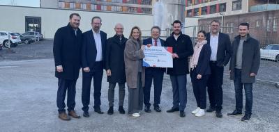 Eine Personengruppe steht vor einem mehrstöckigen Gebäude.