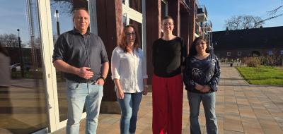 Vier Personen stehen vor einem Gebäude.