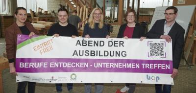 Fünf Personen stehen in einer Werkstatt.
