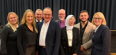 Eine Personengruppe steht vor einem Vorhang.