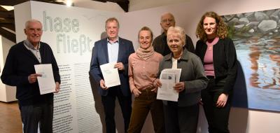 Sechs Personen stehen in einer Ausstellung nebeneinander.