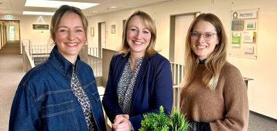 Drei Personen an einem Stehtisch in einem Bürogebäudeflur