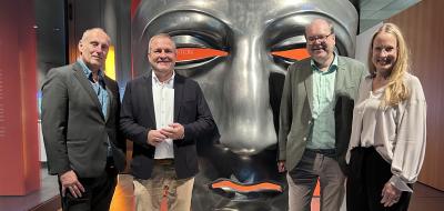 Vier Personen vor einer übergroßen römischen Maske