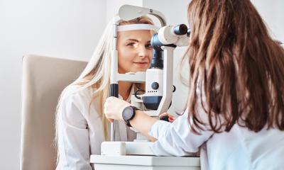 Augenoptikern untersucht Augen einer Kundin