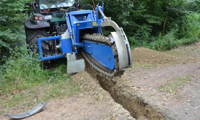 Eine Baumaschine steht an einem Waldweg.