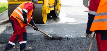 Straßenbauarbeiter verteilen Schotter