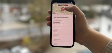 Eine Hand hält ein Smartphone in die Kamera.