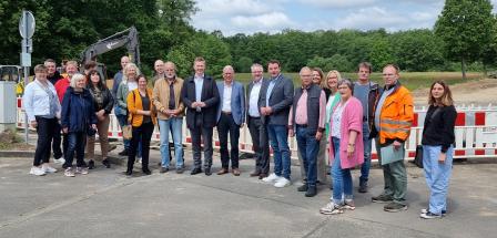 Eine Personengruppe steht vor der Absperrung einer Straßenbaustelle
