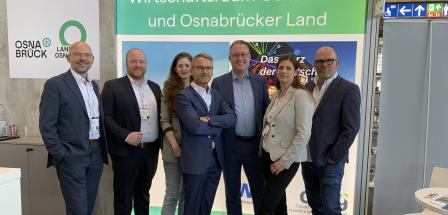 Eine Personengruppe steht auf einem Messestand.