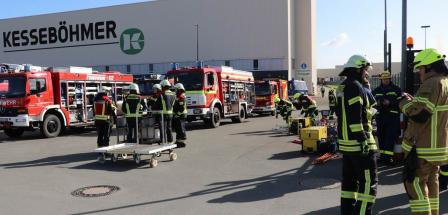 Feuerwehrfahrzeuge stehen vor einer Werkhalle.