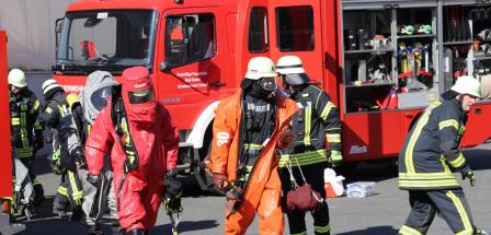 Personen in Schutzkleidung vor einem Feuerwehrfahrzeug