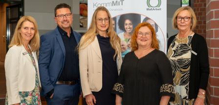 5 Personen vor Plakat