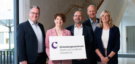 Fünf Personen stehen im Treppenhaus eines Bürogebäudes.
