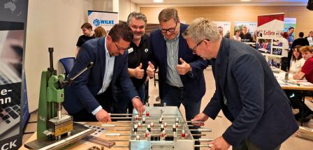 Vier Personen stehen an einem Kickertisch.