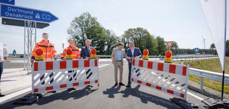 Fünf Personen öffnen einen Straßenbauabsperrung.