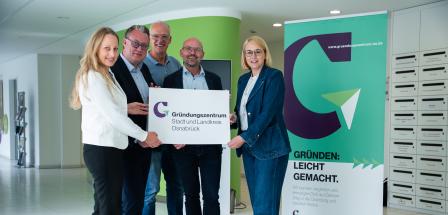 Fünf Personen stehen im Foyer eines Gebäudes.