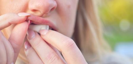 Frau schiebt sich Nicotine Pouches unter die Lippe
