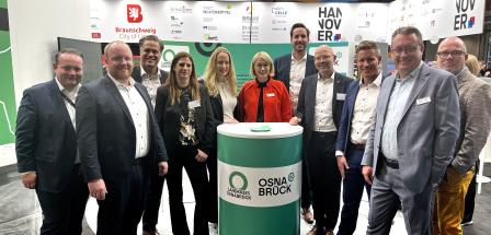 Personengruppe auf einem Messestand schaut in die Kamera.