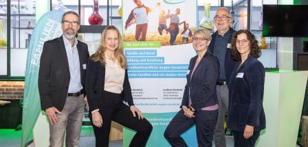 Fünf Personen stehen neben einem Rollup-Poster.