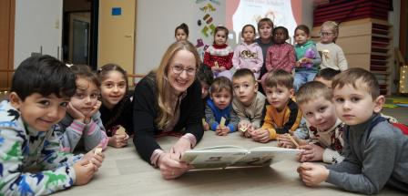 Eine Personengruppe liegt auf dem Boden eines Raumes und schaut in die Kamera.