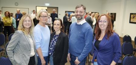 Fünf Personen stehen nebeneinander in einem Raum.