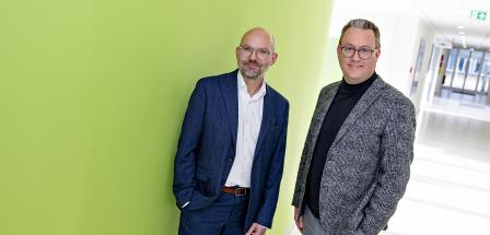 Zwei Personen stehen in einem Gebäudeflur.