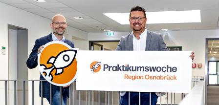 Zwei Personen mit Pappschild stehen in einem Treppenhaus.