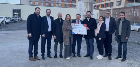 Eine Personengruppe steht vor einem mehrstöckigen Gebäude.