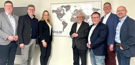 Sieben Personen stehen vor einer Weltkarte.