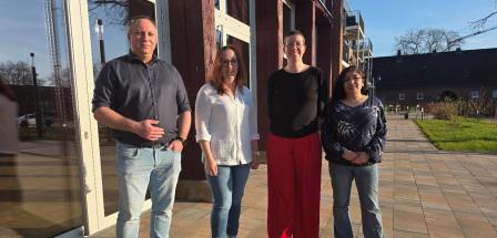 Vier Personen stehen vor einem Gebäude.