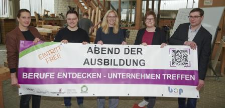 Fünf Personen stehen in einer Werkstatt.