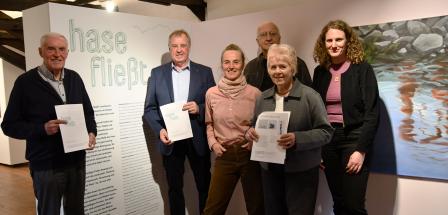 Sechs Personen stehen in einer Ausstellung nebeneinander.