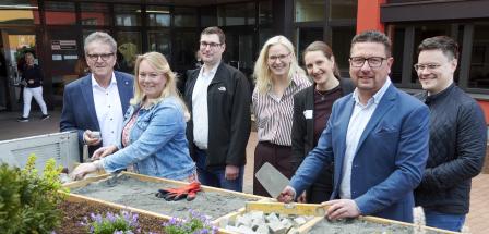 Sieben Personen stehen vor einem Gebäude.