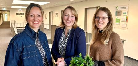 Drei Personen an einem Stehtisch in einem Bürogebäudeflur