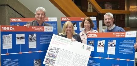 Vier Personen stehen zwischen Ausstellungstafeln