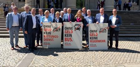 Personengruppe mit Plakaten vor einem Gebäude mit Säulenportal
