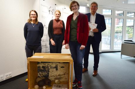 Wanderausstellung Kreishaus "Lebensbilder" Vier Personen stehen in einem Foyer hinter einem Ausstellungsexponat.