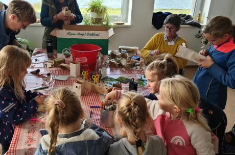 Kinder sitzen um einen Tisch herum und basteln.