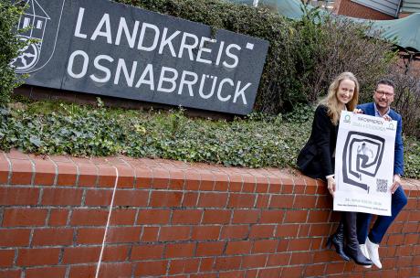 Landrätin und Maßarbeit-Vorstand Hellmers auf einer Mauer sitzend