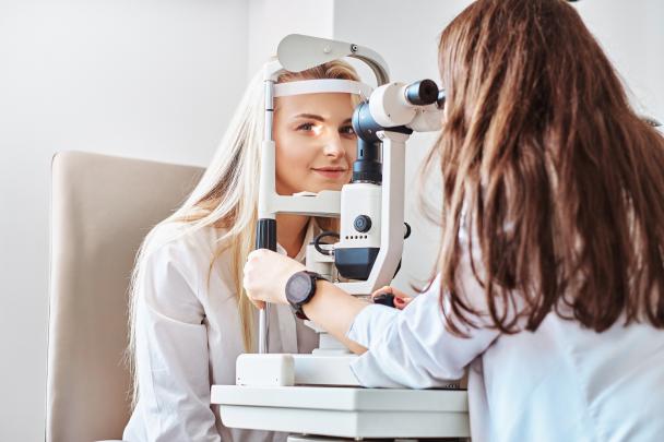 Augenoptikern untersucht Augen einer Kundin