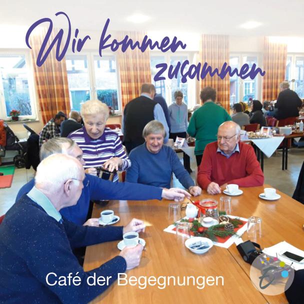 Eine Personengruppe sitzt an einem Tisch mit Kaffeetassen vor sich.