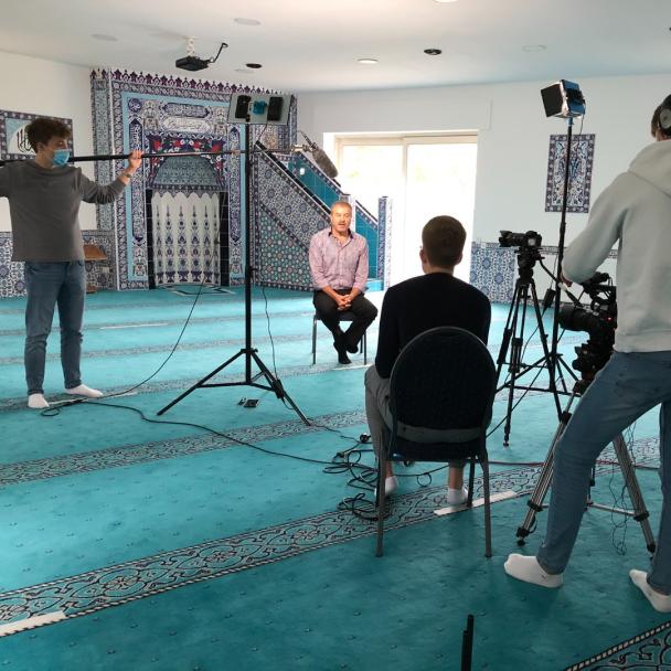 Ein Kamerateam interviewt im Gebetsraum einer Moschee eine Person.