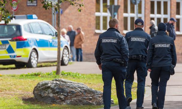 Mitarbeiter eines Ordnungsamtes auf der Straße, Polizeifahrzeug im Bild sichtbar
