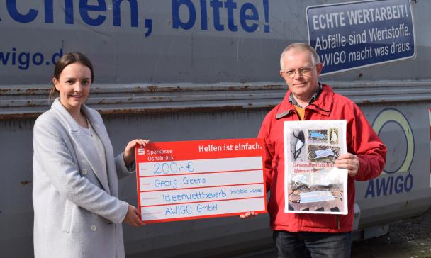 Emily Meyer (links) aus der Unternehmenskommunikation der AWIGO überreichte Georg Geers (rechts) für seine Fotocollage „Lost Mask“ das Preisgeld am Recyclinghof Ankum.