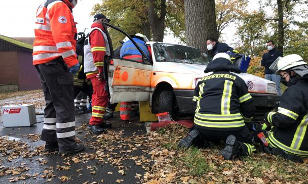 Einsatzkräfte von Rettungsdiensten und Feuerwehr an einem Unfallauto