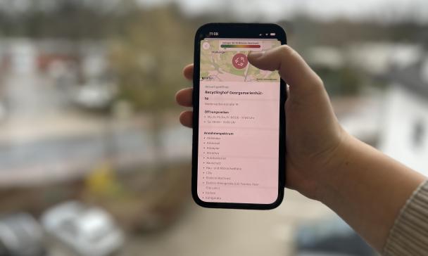 Eine Hand hält ein Smartphone in die Kamera.