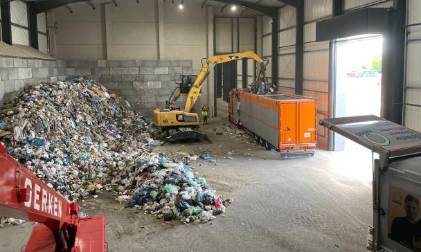 Innenansicht einer Lagerhalle mit Bagger und LKW