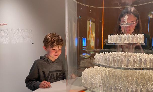 Zwei Personen schauen in eine Vitrine in einer Ausstellung.